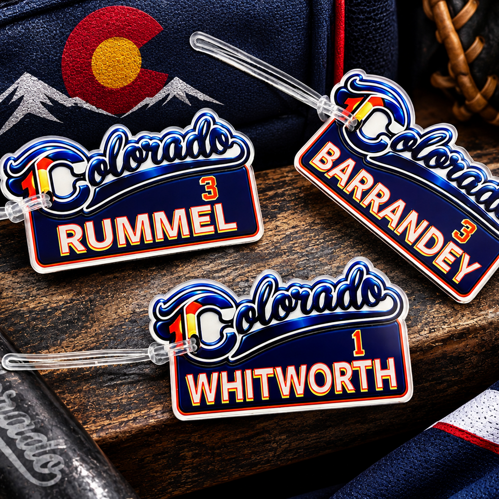 Three personalized luggage tags featuring the Colorado Buffaloes logo and player names Rummel, BarranDEY, and Whitworth, displayed on a wooden surface with Colorado-themed sports props.