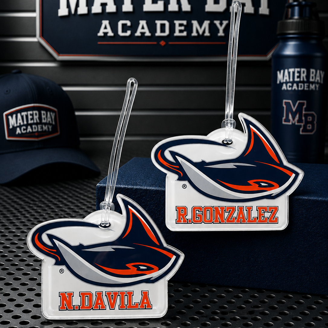 Two Mater Bay Academy luggage tags featuring the school's shark mascot, with personalized names 'R. GONZALEZ' and 'N.